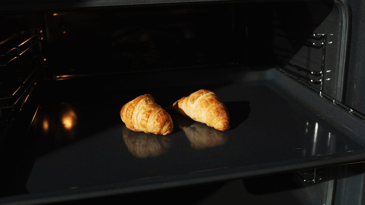 Golden croissants baking in an oven, capturing the perfect homemade pastry moment.